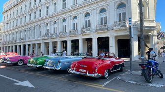 Bunte Oldtimer parken vor einem historischen Gebäude in Havanna - Kuba Reise mit Kindern