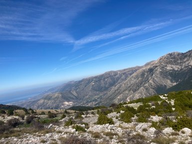 Ein atemberaubender Blick auf die Berge von Llogara Nationalpark, unter einem strahlend blauen Himmel mit sanften Wolken.