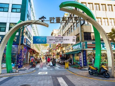 Der Eingang zum Gukje-Markt zeigt ein großes, geschwungenes Tor mit einem blauen Schild und geschäftigen Straßenständen.