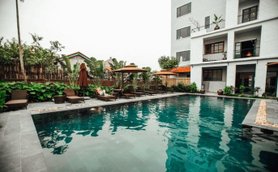Ein ruhiger Hotelpool umgeben von üppigem Grün und gemütlichen Liegen, ideal zum Entspannen und Erholen.
