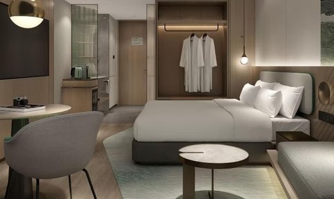 Ein modernes Hotelzimmer mit einem großen Bett, einem gemütlichen Sessel und einem kleinen Tisch, ideal für Entspannung.