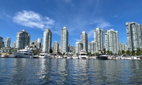 Die Skyline von Vancouver spiegelt sich im ruhigen Wasser, umgeben von modernen Wolkenkratzern und Yachten im Hafen.