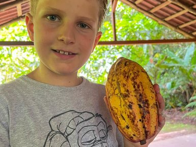 Junge zeigt stolz eine Kakaopflanze bei der Schokoladentour im Tirimbina Reservat – Costa Rica Familienreise