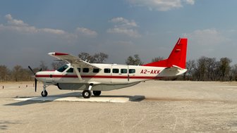 Das Flugzeug A2-AKK ist auf einer staubigen Landebahn geparkt, während die Sonne über der afrikanischen Landschaft scheint.