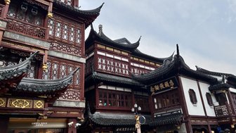 Traditionelle Holzarchitektur in Shanghai mit kunstvollen Dächern und geschäftiger Menschenmenge auf der Straße.