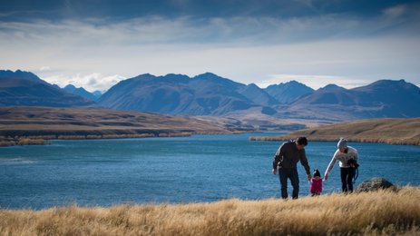 Eine Familie genießt einen sonnigen Tag am Wasser, während die Berge im Hintergrund majestätisch aufragen.