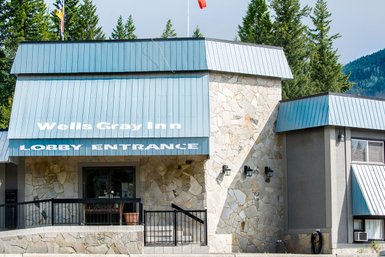 Der Eingangsbereich des Wells Gray Inn zeigt eine moderne Fassade mit Steinverkleidung und einem blauen Dach.