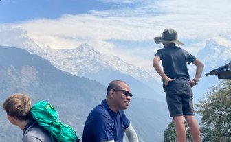 Ein Junge mit einem Hut steht nachdenklich auf einem Felsen und blickt auf die majestätischen schneebedeckten Berge.