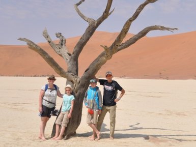 Eine Familie steht neben einem trockenen Baum in der Wüste - Namibia Rundreise mit Kindern