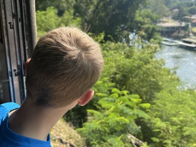 Junge blickt aus Fenster bei Zugfahrt mit Death Train - Thailand mit Kindern