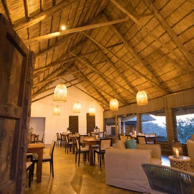 Ein einladendes Restaurant mit einem hohen Strohdach, warmem Licht und rustikalen Holzmöbeln, ideal für gesellige Abende.