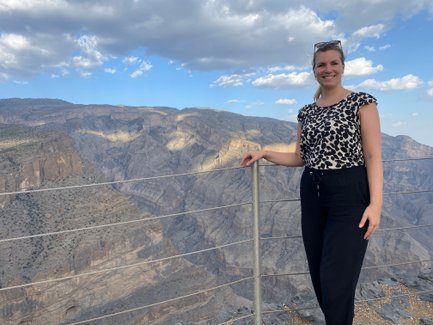 Frau steht vor der Felslandschaft des Jebel Shams und lässt sich fotografieren – Oman Familienreise