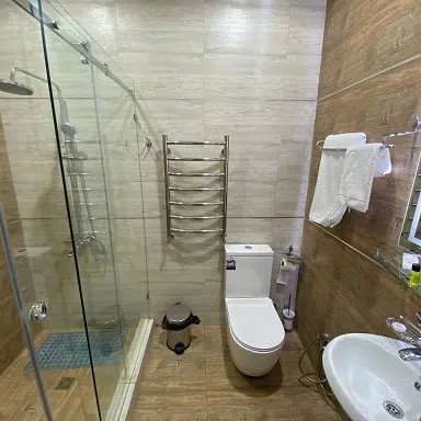 Ein modernes Badezimmer mit einer gläsernen Duschkabine, einem WC und einem eleganten Waschbecken, das gut beleuchtet ist.
