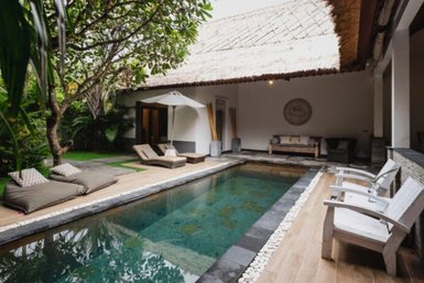 Ein eleganter Innenhof mit einem glitzernden Pool, umgeben von üppigem Grün und gemütlichen Liegen zum Entspannen.