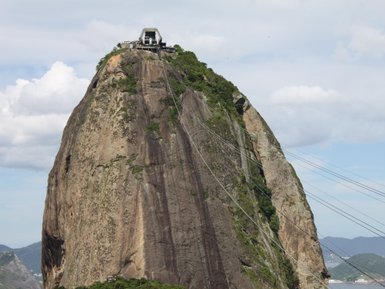 Der Zuckerhut erhebt sich majestätisch über die Stadt Rio de Janeiro, umgeben von üppigem Grün und wolkenverhangenem Himmel.