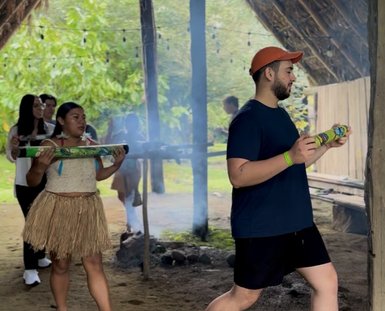 Eine Gruppe von Menschen in traditioneller Kleidung führt eine Zeremonie in einer rustikalen Umgebung mit Rauch durch.
