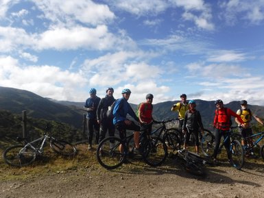 Eine Gruppe von Mountainbikern posiert fröhlich vor einer beeindruckenden Berglandschaft im Los Nevados Nationalpark.