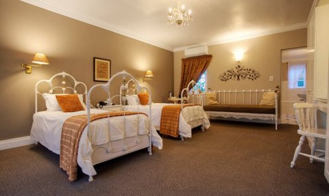 Ein gemütliches Zimmer mit zwei Betten, warmen Farben und einem eleganten Kronleuchter an der Decke.