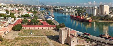 Ein Blick auf die Festung Ozama in Santo Domingo, umgeben von grünen Bäumen und dem glitzernden Wasser des Flusses.
