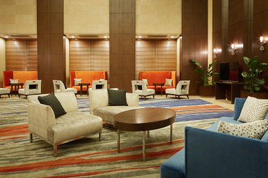 Ein eleganter Foyerbereich mit modernen Möbeln, der eine einladende Atmosphäre mit warmen Farben und stilvollen Akzenten schafft.