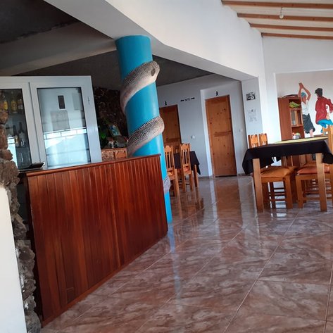 Ein einladendes Restaurant mit Holzstühlen und einem bunten blauen Pfeiler, dekoriert mit einem Fischmuster.