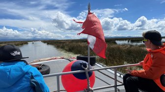 Zwei Kinder sitzen auf einem Boot, während sie die ruhige Wasserlandschaft des Titicaca-Sees genießen.