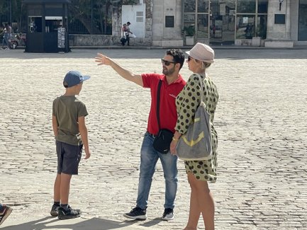 Ein Stadtführer erklärt einem Jungen und einer Frau etwas auf einem gepflasterten Platz in Havanna.