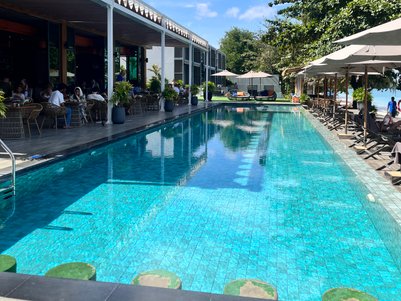 Ein einladender Poolbereich mit klarem Wasser, umgeben von modernen Liegen und schattenspendenden Sonnenschirmen.