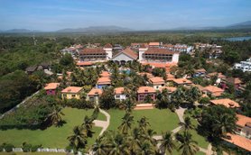 Eine Luftaufnahme des Radisson Blu Resorts in Goa, umgeben von üppigem Grün und bunten Gebäuden mit roten Dächern.