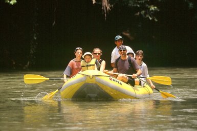 Fröhliche Gruppe paddelt im gelben Rafting-Boot – Costa Rica Reise mit Kindern