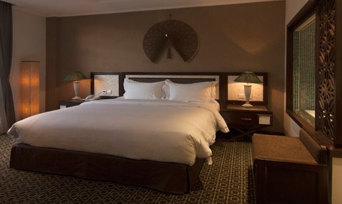 Ein elegantes Hotelzimmer mit einem großen Bett, stilvollen Lampen und einem Fenster, das auf eine malerische Aussicht blickt.