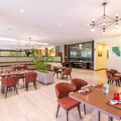 Ein modernes Restaurant mit eleganten Holztischen und stilvollen Stühlen, dekoriert mit Pflanzen und sanfter Beleuchtung.