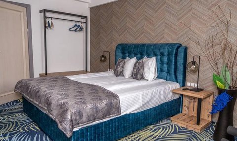 Ein stilvolles Schlafzimmer mit einem blauen Samtbett, dekoriert mit eleganten Kissen und einem modernen Holzbeistelltisch.