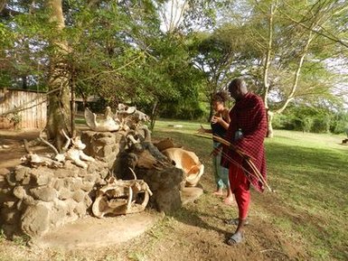 Ein Maasai-Krieger zeigt einem Besucher traditionelle Jagdtechniken in einem kulturellen Camp in den Loita Hills.