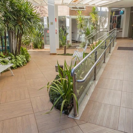 Der Eingangsbereich des Nadia Confort Hotels präsentiert sich freundlich mit einem Gehweg, umgeben von grüner Vegetation.