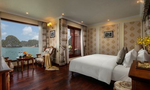 Ein elegantes Zimmer mit Blick auf die Halong-Bucht, ausgestattet mit einem großen Bett und stilvollen Möbeln.