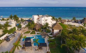 Ein Blick auf das Hotel Ojo de Agua, umgeben von Palmen und einem einladenden Pool, mit dem Meer im Hintergrund.