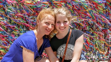 Eine glückliche Mutter und Tochter posieren vor einer bunten, mit Bändern geschmückten Wand in Salvador.