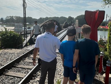 Guide zeigt Touristen die berühmte Brücke am River Kwai - Thailand mit Kindern