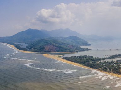 Eine atemberaubende Küstenlandschaft mit sanften Wellen, die an einen goldenen Strand schlagen, umgeben von grünen Hügeln.