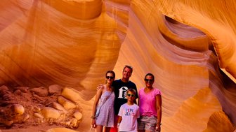 Eine Familie steht in der beeindruckenden Antelope Canyon, umgeben von orangefarbenen Sandsteinformationen und weichem Licht.