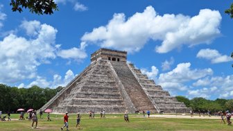 Die beeindruckende Pyramide von Chichén Itzá erhebt sich majestätisch unter einem strahlend blauen Himmel mit weißen Wolken.