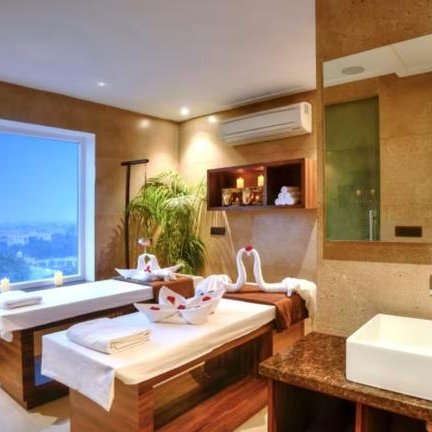 Ein elegantes Spa mit zwei Massagetischen, dekoriert mit weißen Handtüchern und Schwänen aus Handtüchern, bietet Entspannung.