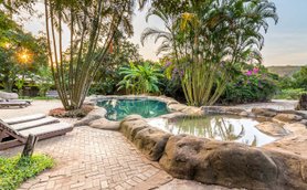 Ein einladender Außenbereich mit einem natürlichen Pool, umgeben von üppigem Grün und Palmen, ideal zum Entspannen.