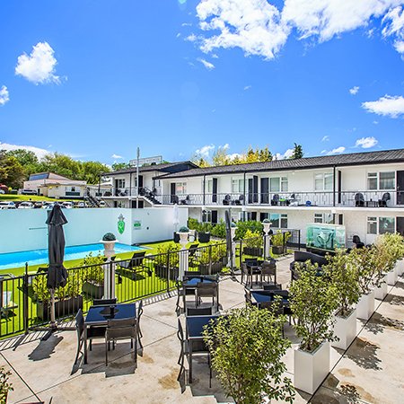 Ein einladender Außenbereich eines Boutique-Hotels mit einem Pool und modernen Sitzgelegenheiten umgeben von grünen Pflanzen.