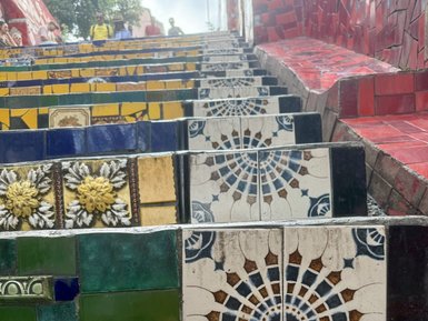 Bunte, mosaikartige Treppenstufen mit verschiedenen geometrischen Mustern und floralen Designs ziehen sich nach oben.