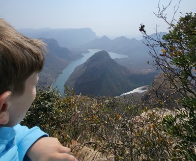 Ein Kind steht am Rand des Blyde River Canyons und blickt fasziniert auf die Landschaft – Südafrika mit Kindern