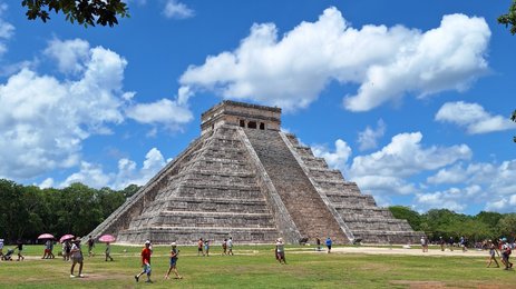 Die beeindruckende Pyramide von Chichén Itzá erhebt sich majestätisch unter einem strahlend blauen Himmel mit weißen Wolken.