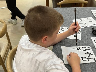 Kind schreibt chinesische Schriftzeichen bei einem Kalligrafie-Workshop – China Reise mit Kindern