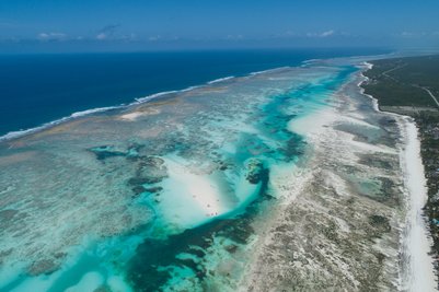 Ein atemberaubender Blick auf die Küste mit klarem, türkisfarbenem Wasser und feinem, weißen Sandstrand unter einem strahlend blauen Himmel.